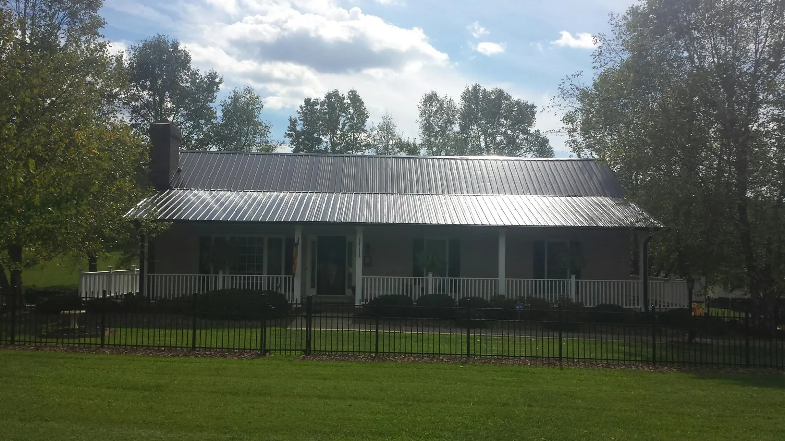 Gray metal roof on a brick ranch with a full width front porch — Gutter Guard Installation work by our crew in East Hartford