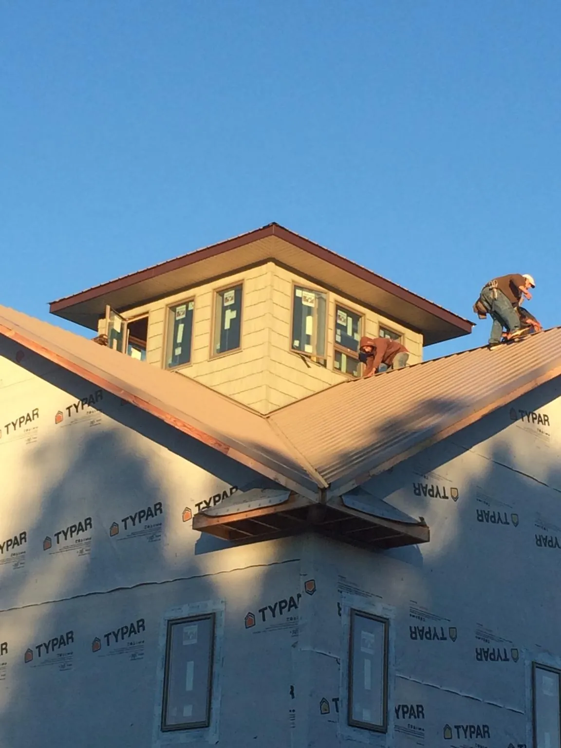 Roofers working around a rooftop cupola on a new metal roof at sunset — Roof Waterproofing in East Hartford by Roofing Brothers